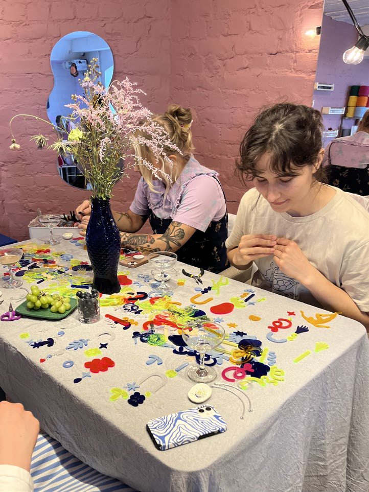Participants assembling colourful acrylic suncatcher pieces at an Idle workshop table